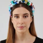 Frontal view of a woman wearing the Maria Blueberry Headband, showcasing its vibrant floral print on a white fabric.
