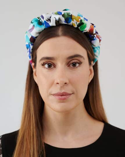 Frontal view of a woman wearing the Maria Blueberry Headband, showcasing its vibrant floral print on a white fabric.
