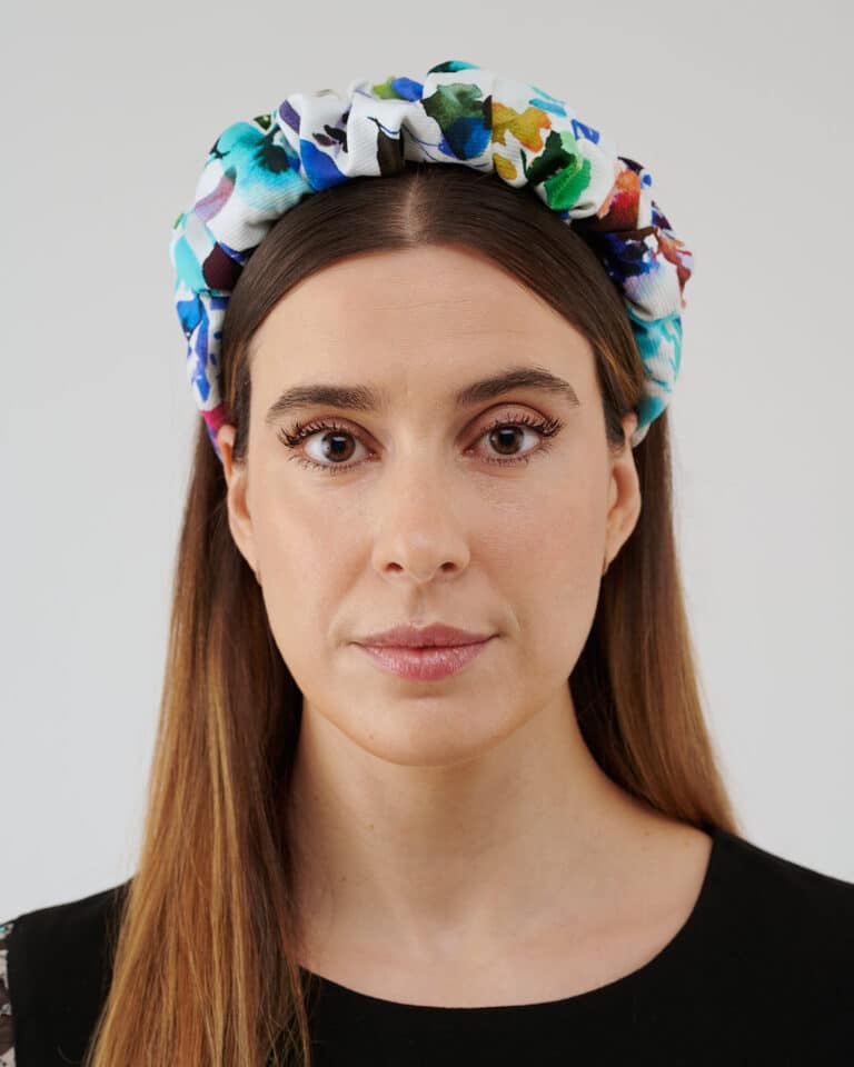 Frontal view of a woman wearing the Maria Blueberry Headband, showcasing its vibrant floral print on a white fabric.