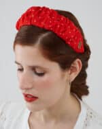 Close-up of a model with her eyes closed, showcasing the Watermelon Headband, featuring red silk crepe fabric with white polka dots and an elegant gold logo detail.