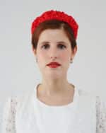 Front view of a model wearing a vibrant red Watermelon Headband adorned with small white polka dots, contrasting her white Maria Lily Mini-Dress with delicate lace fabric.