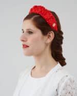 Side profile of a model showcasing the Watermelon Headband with white polka dots and a gold logo plate, complementing her elegant hairstyle and the lace detail of the Maria Lily Mini-Dress.