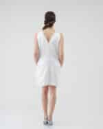 Rear view of a model in the Maria Daisy Mini Dress featuring a v-back with button details and the vibrant Tulip Headband, paired with light blue strappy heels.