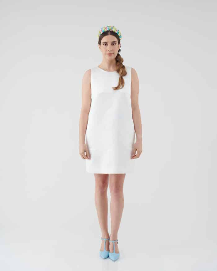 Elegant model in a Maria Daisy Mini Dress paired with the vibrant Tulip Headband, standing confidently in blue ankle-strap heels against a white backdrop.
