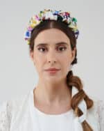 Front view of a model showcasing the vibrant Lemon Headband with colorful floral patterns, set against her braid and the white lace of the Maria Lily Mini Dress.