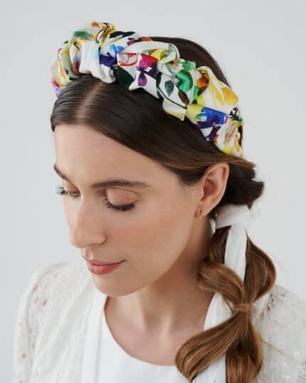 Model in a contemplative pose wearing the vibrant Lemon Headband, with a white lace dress and hair styled in a loose braid.