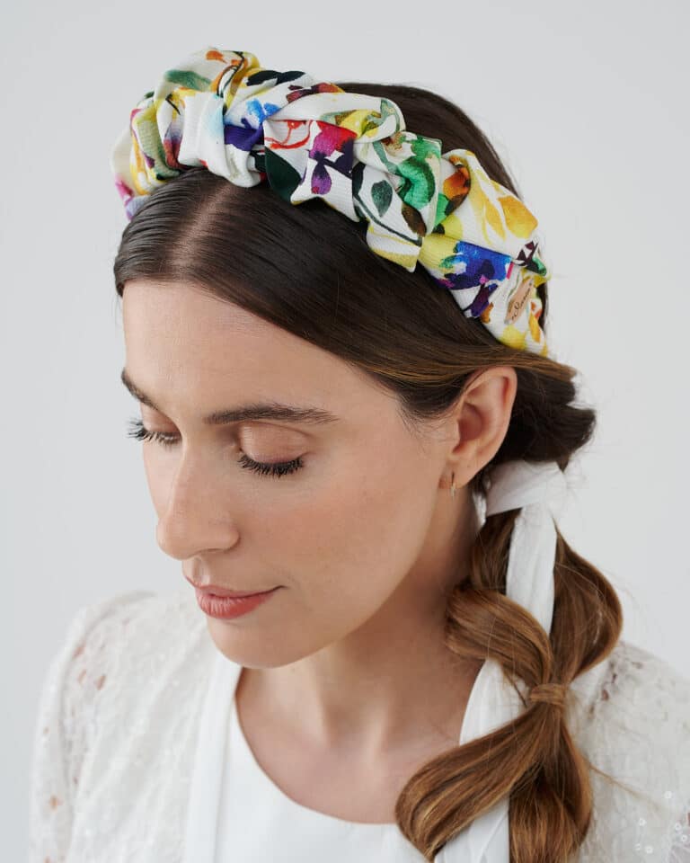 Model in a contemplative pose wearing the vibrant Lemon Headband, with a white lace dress and hair styled in a loose braid.