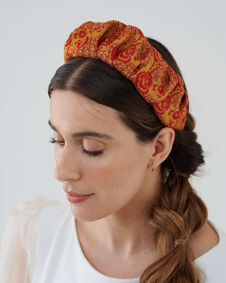 Profile view of a woman with a braided hairstyle wearing the Maria Fern Headband in red and yellow, and the Maria Peony Mini Dress.