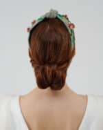 Rear view of the Greenery Headband with hand-embroidered details and a model's twisted low bun hairstyle, complemented by the elegant Maria Jasmine Mini Dress.