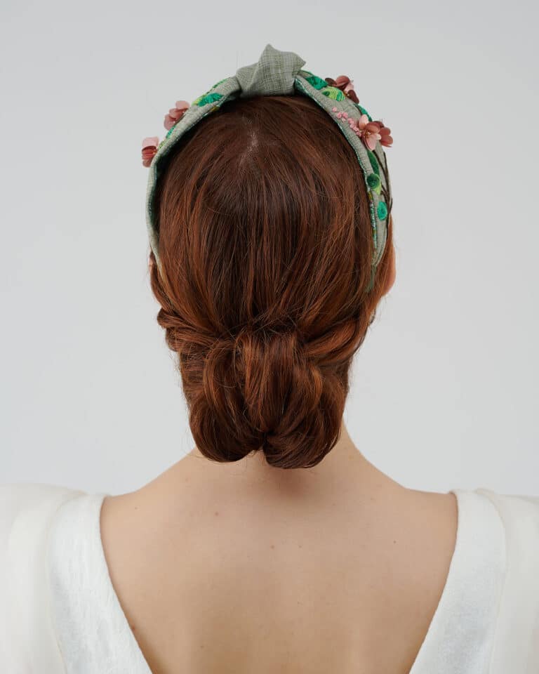 Rear view of the Greenery Headband with hand-embroidered details and a model's twisted low bun hairstyle, complemented by the elegant Maria Jasmine Mini Dress.