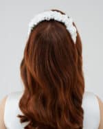 Rear view of a woman with auburn hair wearing a white Daisy Headband.