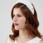 Side view of a woman with auburn hair and red lipstick, wearing a white Daisy Headband.