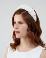 Side view of a woman with auburn hair and red lipstick, wearing a white Daisy Headband.