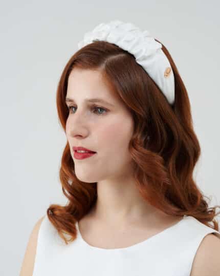 Side view of a woman with auburn hair and red lipstick, wearing a white Daisy Headband.