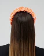 Rear view of a woman wearing the Maria Coral Headband with a rich orange and white floral print, over long, straight brown hair.
