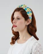 Profile view of a woman modeling the Tulip Headband, showcasing the colorful silk devoré fabric, alongside the Maria Lily Mini Dress with delicate lace detailing.