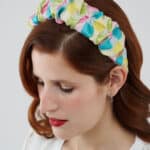 Close-up of a woman with auburn hair and red lipstick wearing the Tulip Headband, made with multicolored silk devoré fabric.