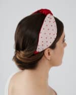 Profile view of a model wearing the Strawberry Headband, showcasing its red crystal bead embroidery and red bow, paired with the Maria Jasmine Mini Dress.