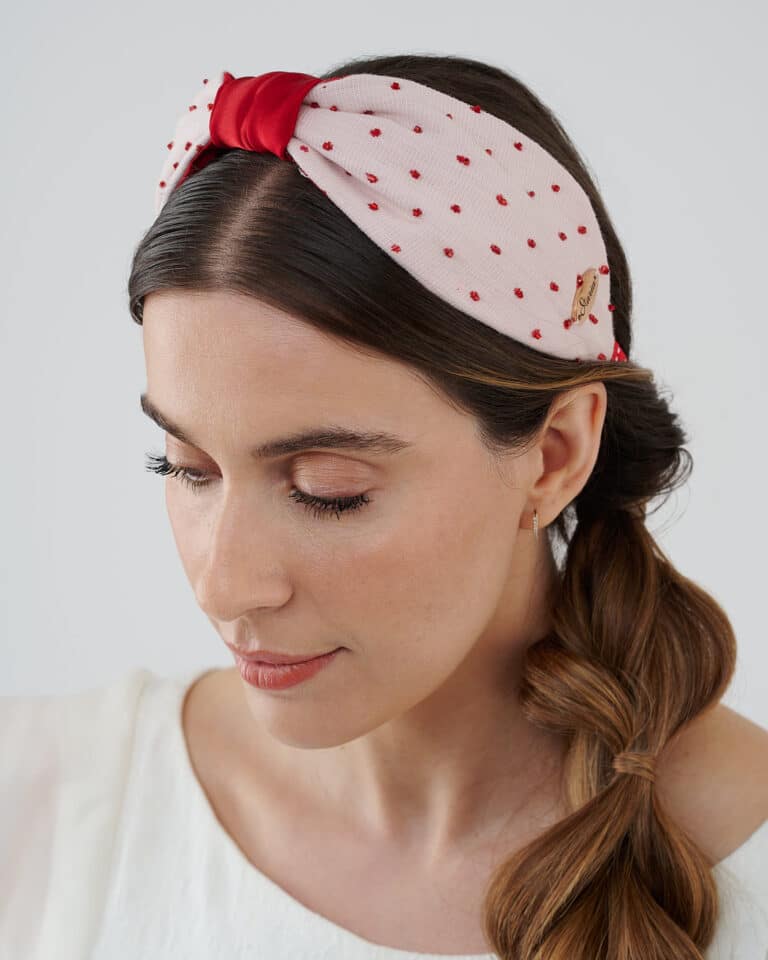 Side view of a model wearing the Strawberry Headband, with hand-embroidered red crystal beads on a polka-dotted fabric, matched with the Maria Jasmine Mini Dress.