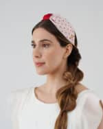 Frontal view of a model wearing the Strawberry Headband with red crystal bead embroidery and a prominent red bow, complemented by the Maria Jasmine Mini Dress.
